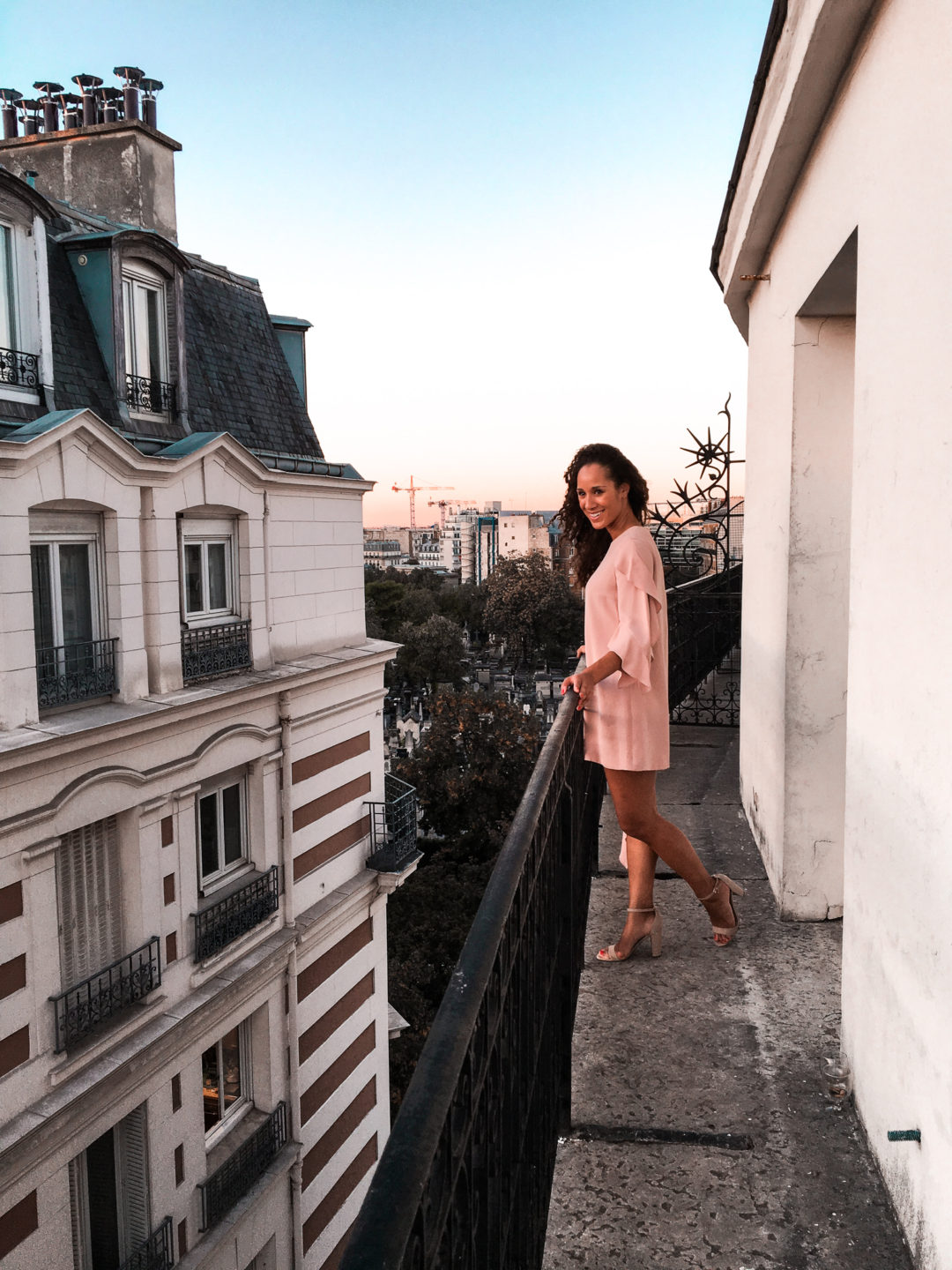 On a balcony in Paris wearing Rent the Runway